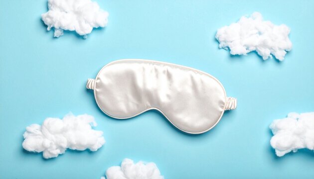 A white sleep mask lies on a light blue surface surrounded by fluffy white clouds.