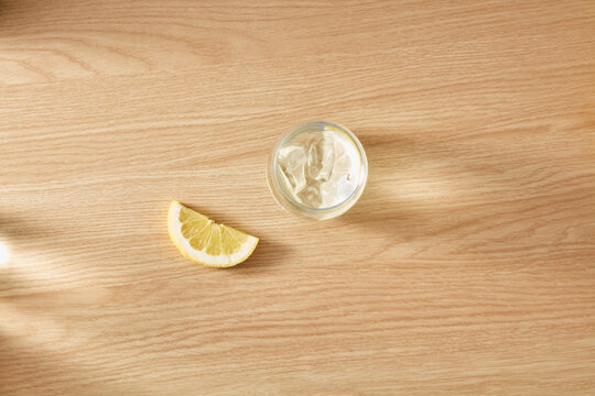 Glass of cold water with ice and lemon slice on wooden table