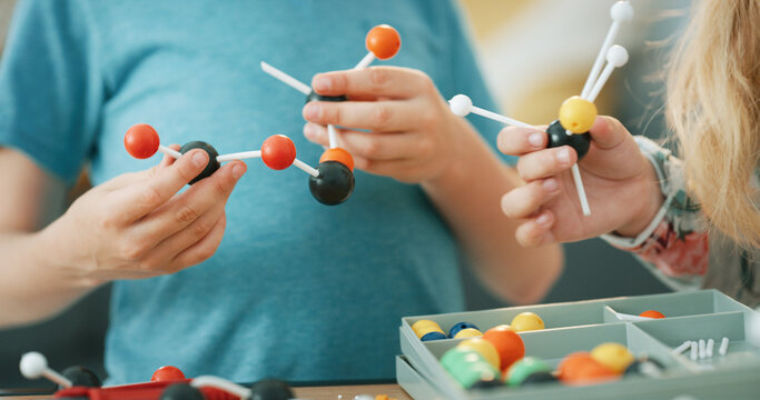 Hands, science and children with atom model for project, discovery or assignment. Learning, toy and siblings with inspection of molecule, particle or element for school homework in house