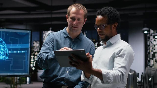 Engineering team using tablet in office, working with AI programming languages. Teamworking colleagues using device in company workplace to do artificial intelligence tech quality assurance.