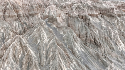 Obraz premium Mountains rise in dry terrain with rocky peaks and slopes under clear sky