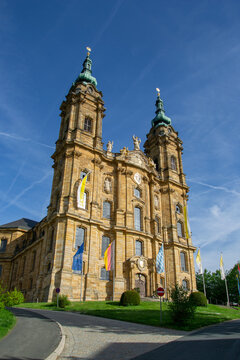 Prachtvolle Westfassade der Basilika Vierzehnheiligen mit Flaggen vor blauem Himmel bei Bad Staffelstein