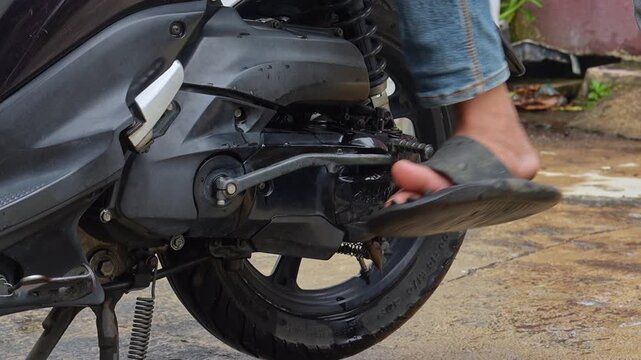 Close-up Hand Washing Motorcycle Wheel with Brush in Outdoor Setting