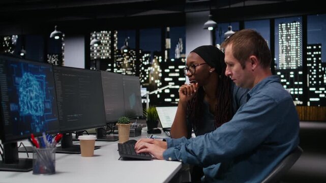 Engineering team in office working to fix bugs in AI systems using computer. Teamworking colleagues troubleshooting neural network errors in tech startup workplace using PC for coding workflows.