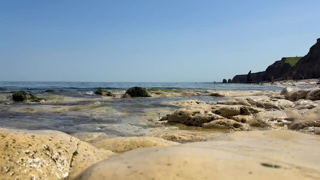 Clear ocean waves crashing on rocky Ryhope Beach on beautiful summer day - Sunderland, UK