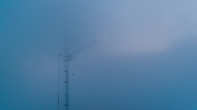 fog over a tower crane at a construction site, time-lapse