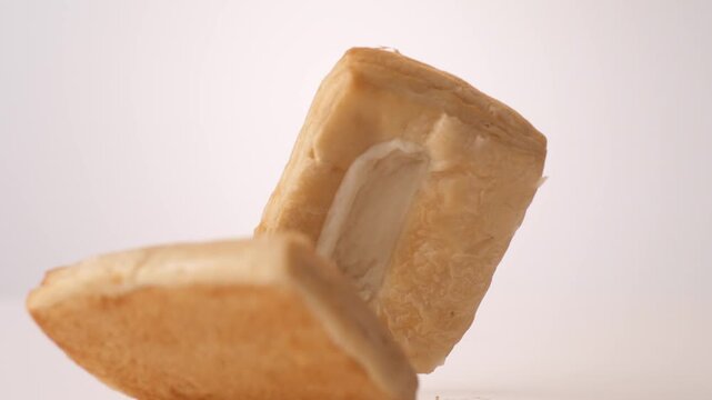 Golden flaky cream-filled danishes bouncing and tumbling on white in slow motion macro studio shot. bakery storefront ads, coffee shop pastry case content, brunch menu reels.