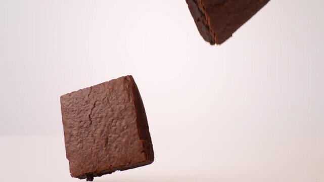 Rich fudgy brownies bouncing and tumbling on white in slow motion macro studio shot. bake sale fundraisers, school lunch content, party dessert tables.
