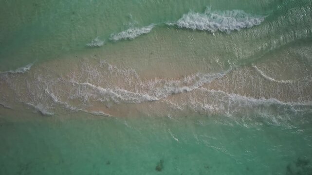 Top-down aerial ascent over Caribbean sea waves lapping over a sandbar in Cayo de Agua, Los Roques, Venezuela