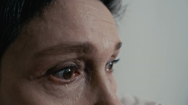 Middle aged Caucasian woman looking around with anxious, panicked eyes in extreme close up. Footage is ideal for mental health awareness campaigns or psychiatric clinic promotions