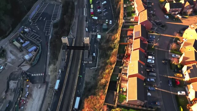 Drone aerial view flying over Morley Railway Station and new build residential estate in Leeds, West Yorkshire, England during golden hour.