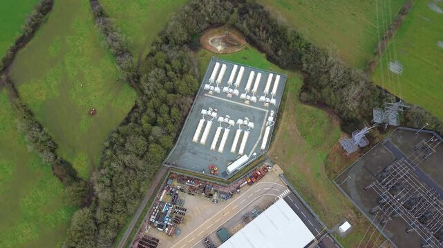 Drone perspective of a massive industrial battery energy storage system BESS alongside an electrical grid substation UK
