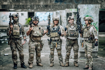 Fototapeta premium Tactical team celebrates mission success raising helmets and fists together in abandoned building