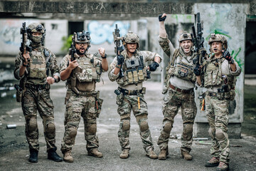 Fototapeta premium Tactical team celebrates mission success raising helmets and fists together in abandoned building