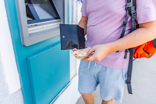 Traveler withdrawing euro cash from an ATM during vacation abroad. Travel budgeting, tourism expenses, international payments and holiday planning concept.