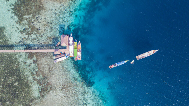 Top Down Aerial View of Boats Moored at a Wooden Pier over a Coral Reef