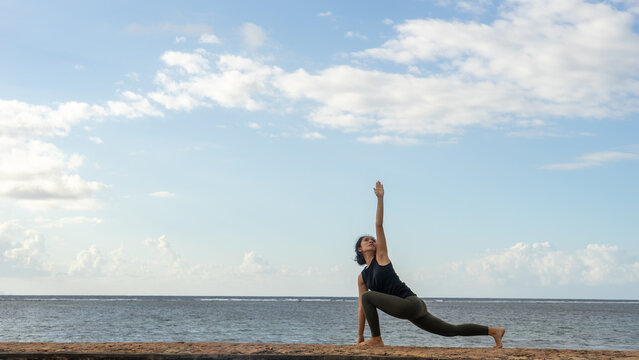 Woman Practicing Extended Side Angle Yoga Pose by the Ocean