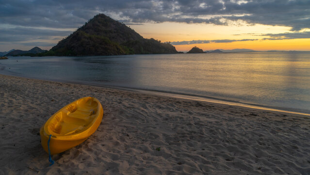 Yellow Kayak on Sandy Beach at Sunset with Mountain Islands Background