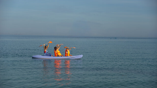 Happy Family Kayaking in Calm Blue Sea Wearing Life Jackets