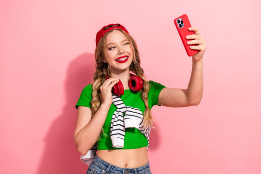 Young stylish girl takes a bright self portrait wearing a green crop top and headphones