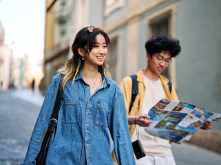 Fototapeta premium Portrait of a smiling couple loking at a map in the city, tourists visiting destination, summer trip exploring