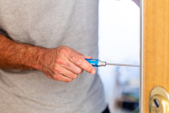 Man repairing door lock with screwdriver at home
