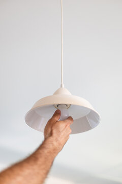 Hand installing led light bulb in ceiling lamp