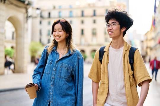 Portrait of a smiling couple walking down the street in the city, tourists visiting destination, summer trip exploring