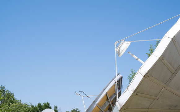 Industrial satellite dish antenna looking up at clear blue sky for telecommunication and broadcasting