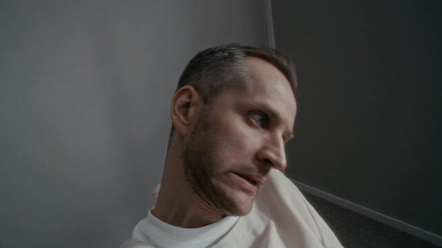 Caucasian middle aged man in patient gown shaking head erratically and looking around with wide eyes, motion blur. Clip is suitable for mental health awareness campaigns or psychiatric clinic videos