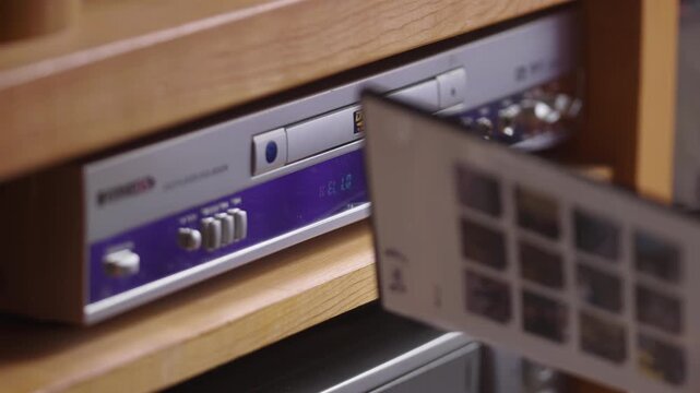 hand switches on a vintage DVD player set inside a warm wooden media unit