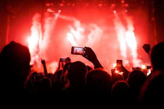 Fan recording live show with smartphone at red light music concert