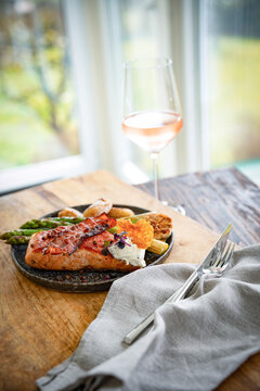 Fried salmon fillet with green asparagus, served with a glass of chilled ros&eacute; wine. Vertical background for gastronomy and lifestyle.