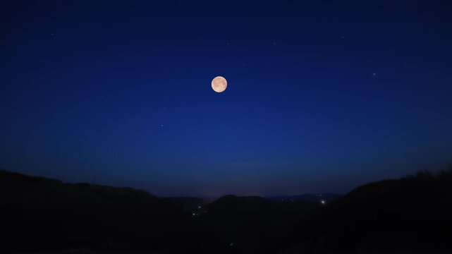 Full Moon on a twilight sky with landscape and tree silhouettes.