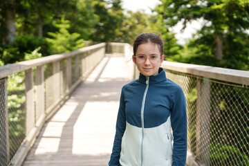 Fototapeta premium Girl walking on treetop walkway in forest adventure park