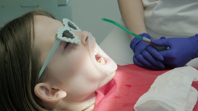 Dentist using saliva ejector tube during child treatment