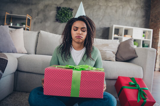 Photo of attractive young woman upset receive bad gift birthday dressed green knitwear outfit cozy day light home interior living room
