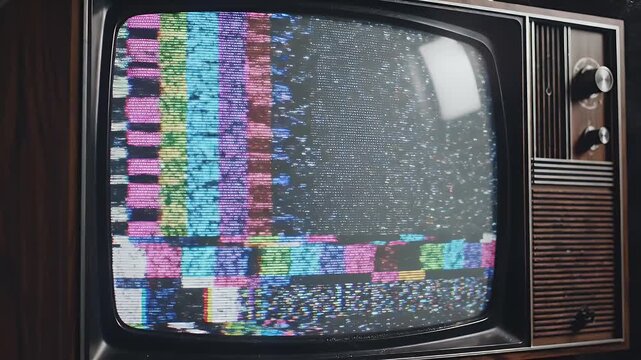 A vintage television set displays static and colored test patterns.