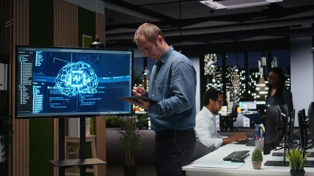 Manager in office using screen to analyze machine learning algorithms built by workers. Startup team leader supervising code written by employees to improve artificial intelligence.