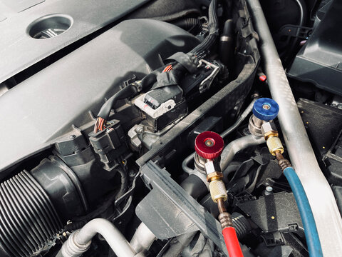 car air conditioning system inspection with manifold gauge set connected inside engine bay show automotive AC pressure testing refrigerant service maintenance and repair diagnostic process professiona