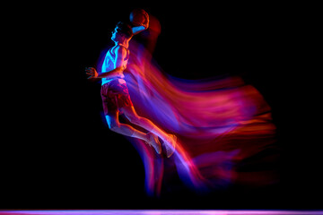 Obraz premium Basketball player jumping with neon motion blur on black studio background. Concept of basketball performance, sport advertising, energy drink campaign, speed, power, event poster.