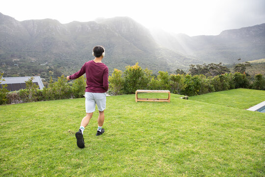 Low wooden bench sitting on manicured lawn near pool edge with mountains rising under sun rays