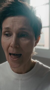 Vertical closeup of middle aged Caucasian woman sticking out tongue and placing small pill on it. Clip is ideal for mental health awareness campaigns or pharmaceutical commercials