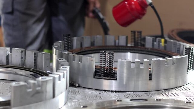 Mechanic applying oil to an automatic transmission clutch pack assembly during a gearbox rebuild in a workshop.