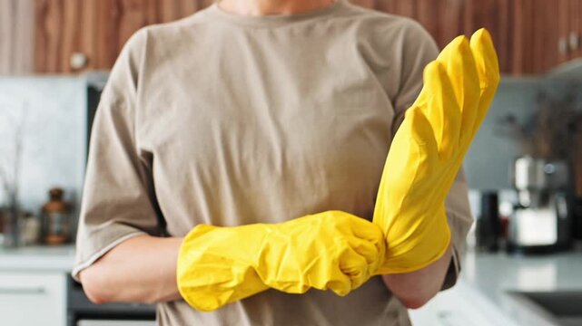 Woman adjusts cleaning gloves securely. Readiness for domestic work and kitchen care is highlighted. Preparation process supports efficient cleaning workflow, hygiene management and sanitary upkeep.