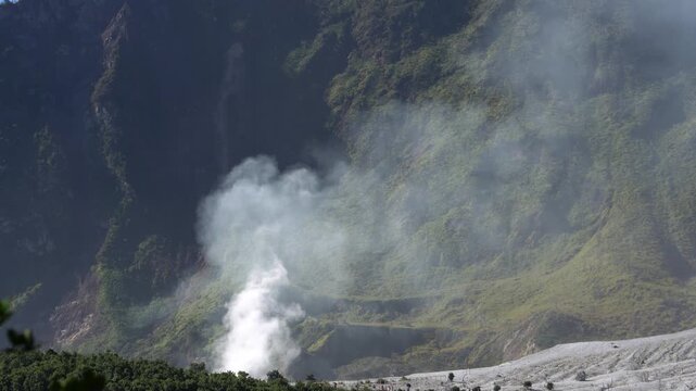 Volcanic landscape with steam rising from a geothermal vent on the slopes of mount papandayan in garut, west java, indonesia