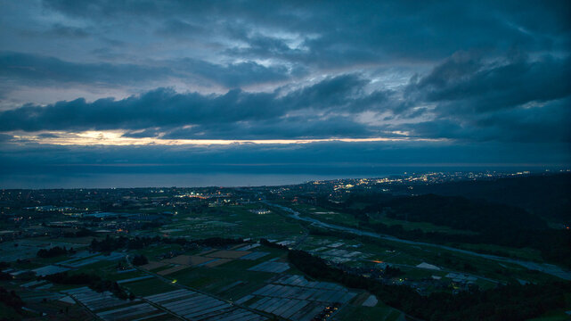 日本の富山県滑川市の丘陵部から見た富山湾や富山市の夕方になり灯りのついてきた様子