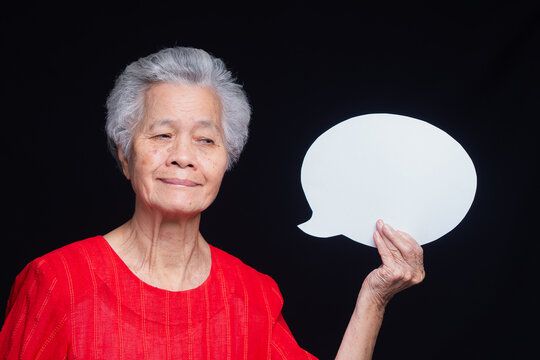 Senior Woman Looking at Blank Speech Bubble on Dark Background

