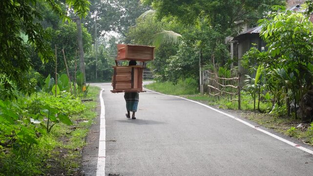 Hardworking vendor carrying wooden furniture for sale