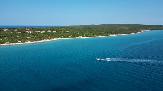 Aerial drone view of a speedboat approaching Silba Island in Croatia across the deep blue Adriatic Sea. Scenic Mediterranean coastline, turquoise waters and a charming island village create an idyllic